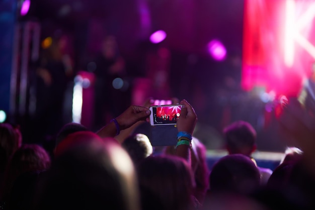 Mano con teléfono graba festival de música en vivo Gente tomando fotografías con teléfono durante el concierto