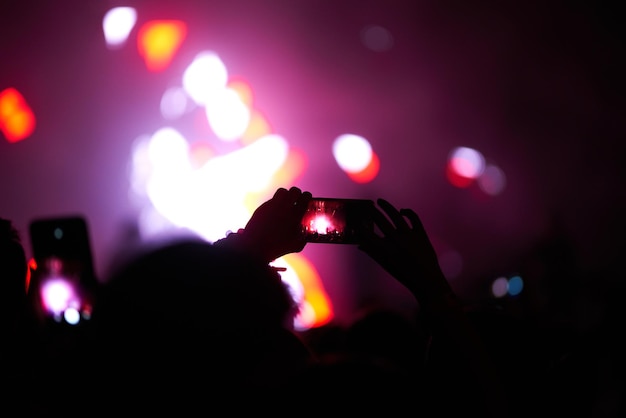 Mano con teléfono graba festival de música en vivo Personas tomando fotografías con teléfonos inteligentes durante el concierto