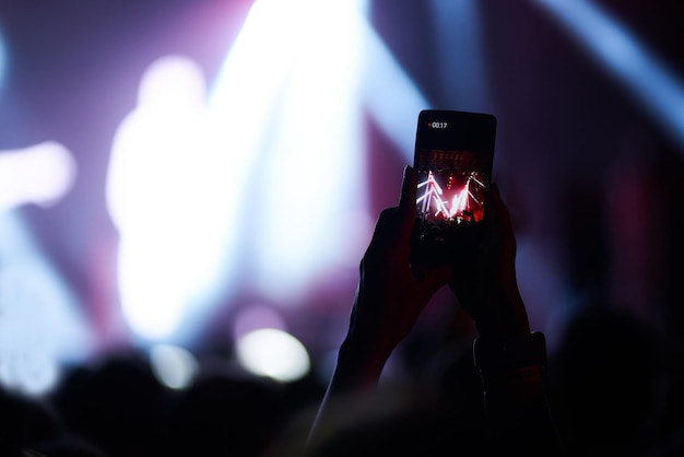 Mano con teléfono graba festival de música en vivo Personas tomando fotografías con teléfonos inteligentes durante el concierto