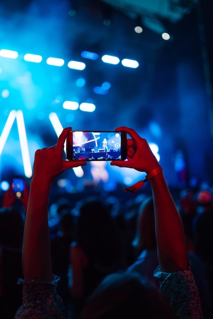 Foto mano con un teléfono graba festival de música en vivo personas tomando fotografías con teléfonos inteligentes