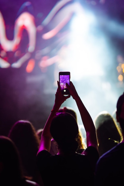 Mano con un teléfono graba festival de música en vivo Personas tomando fotografías con teléfonos inteligentes