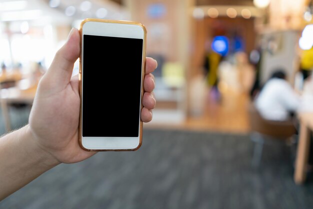 Mano con el teléfono inteligente del hombre de Asia en el concepto de internet de la tecnología digital de la sala de oficina