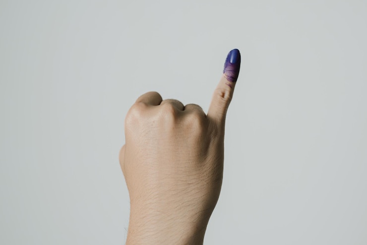 Una mano con tinta púrpura aplicada en el dedo meñique después del pemilu o las elecciones presidenciales indonesias