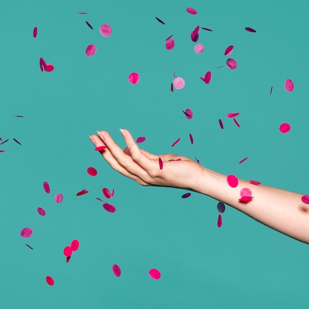 Foto mano tocando el confeti rosa