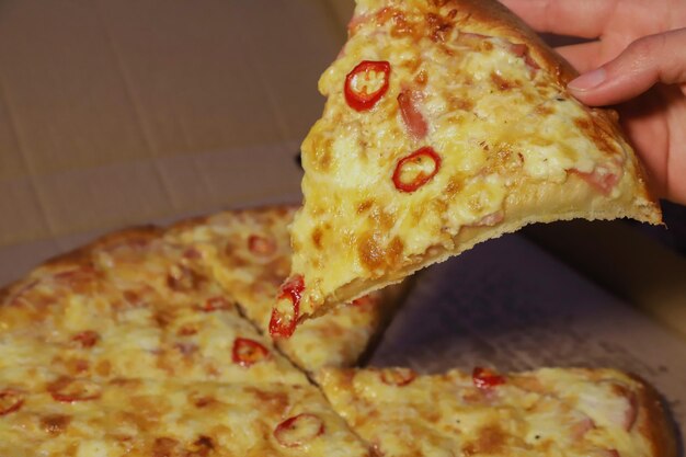 Foto mano toma rebanada de pizza de la caja