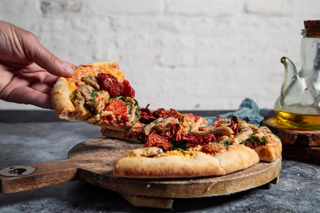 La mano toma un trozo de pizza vegana casera.