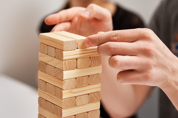 Mano tome una cuadra de la torre de madera sobre fondo blanco juego de mesa de entretenimiento familiar