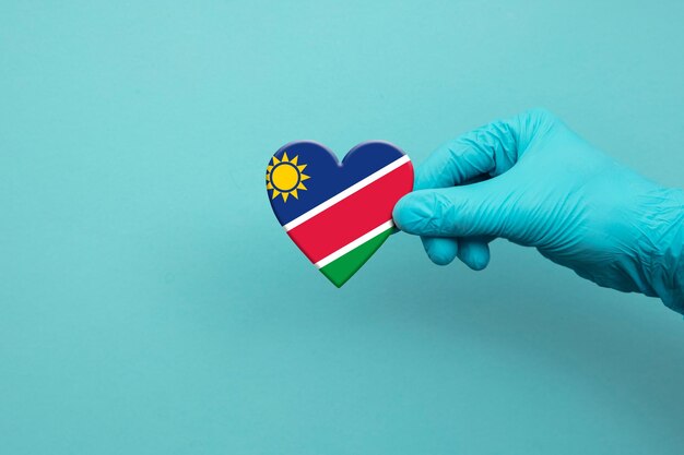 Mano de trabajadores médicos con guante quirúrgico con corazón de bandera de namibia