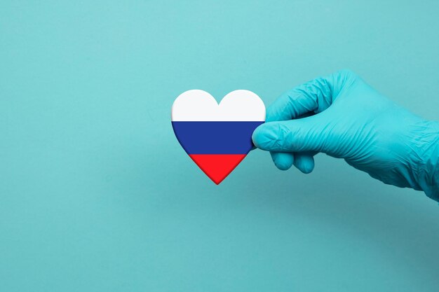 Mano de trabajadores médicos con guante quirúrgico con corazón de bandera de rusia