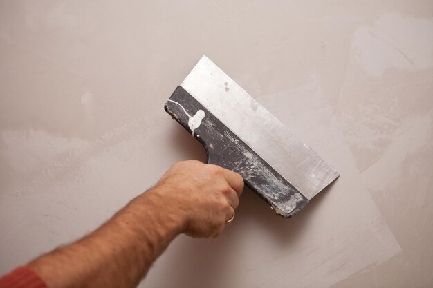 Mano con un trabajo de espátula alinea la pared