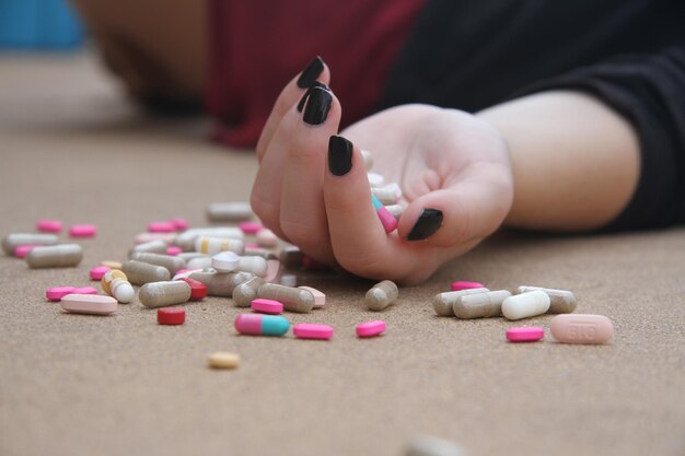 Una mano con una uña negra sostiene un montón de pastillas en el suelo.