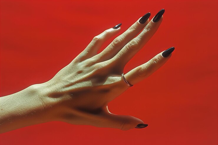 Una mano con uñas negras se extiende sobre un fondo rojo fotografía minimalista composición simple