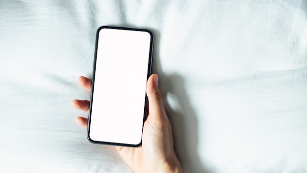 Mano usando la pantalla en blanco del teléfono inteligente en la habitación, durante el tiempo libre.