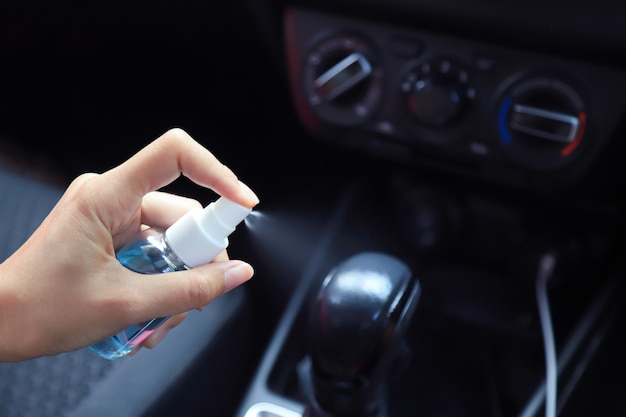 mano usando spray de alcohol para limpiar la palanca de cambio de marchas del virus Corona o bacterias en uso en el automóvil de la vida diaria. prevenir el concepto Covid 19