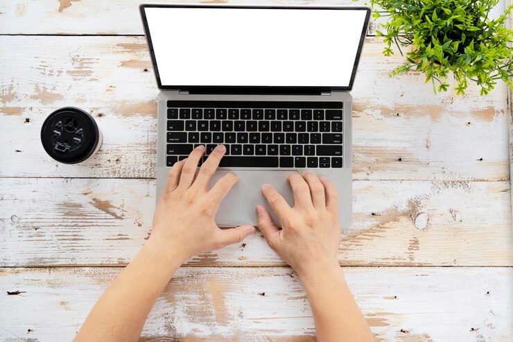 Foto mano usando y tocando en el panel táctil de la computadora portátil con pantalla de escritorio blanca en blanco