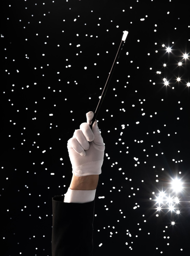 Foto mano con una varita mágica sobre un fondo estrellado negro
