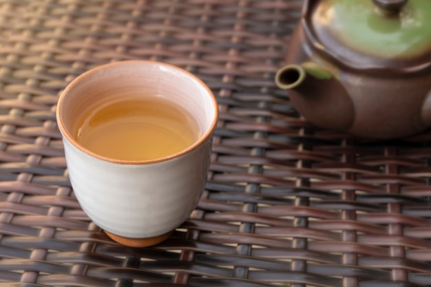 Mano vertiendo té de hierbas caliente saludable en una taza de cerámica al aire libre en una cafetería o restaurante