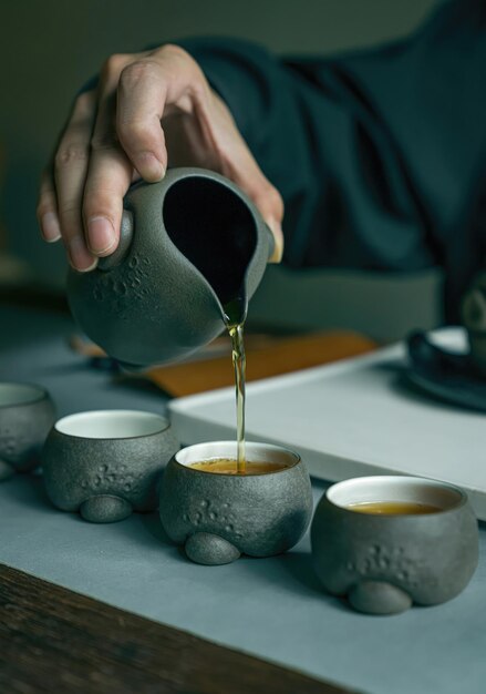 Una mano vierte una taza de té de una tetera.