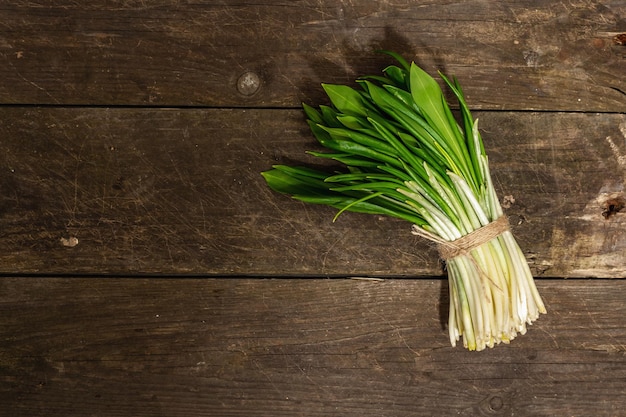 Manojo de cosecha fresca de puerro silvestre ramson de primavera Hojas picantes fragantes en mesa de madera vintage