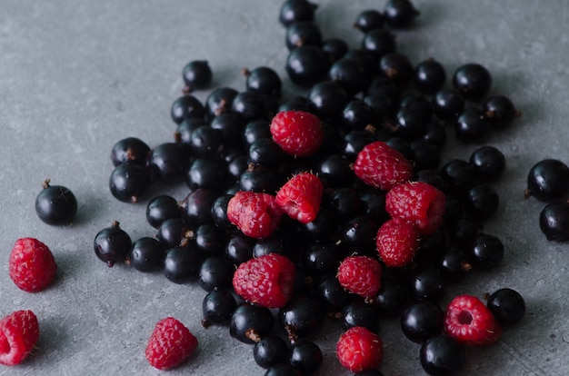 Manojo de grosellas negras y frambuesas en una mesa de cocina gris. Vista de primer plano