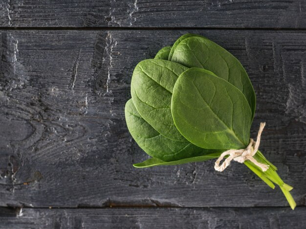 Un manojo de hojas de espinacas frescas atadas con una cuerda sobre una mesa negra. Alimentos para fitness. Comida vegetariana.