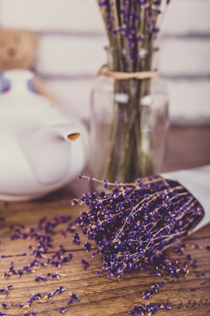 Manojo de lavanda cortada en seco y tetera en la mesa de madera. Ladrillos blancos.