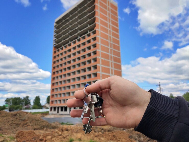 Manojo de llaves de un apartamento en la mano de un hombre en el fondo de un edificio nuevo