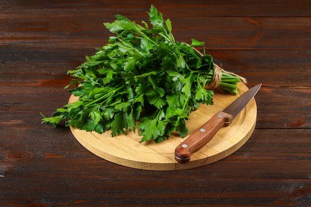 Un manojo de perejil verde en una mesa de madera con un cuchillo