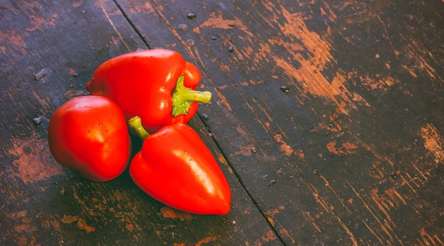 Manojo de pimientos rojos maduros frescos en un viejo fondo de grunge de madera negro con espacio de copia