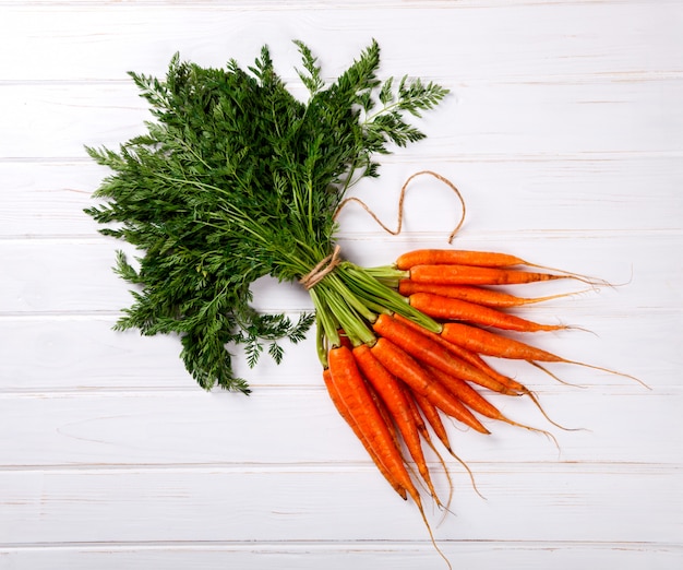 Manojo de zanahorias frescas con hojas verdes sobre un fondo blanco