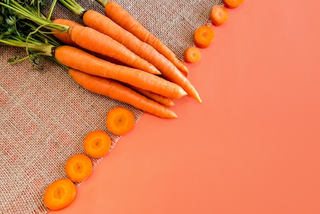 Un manojo de zanahorias sobre un fondo naranja, zanahorias en rodajas