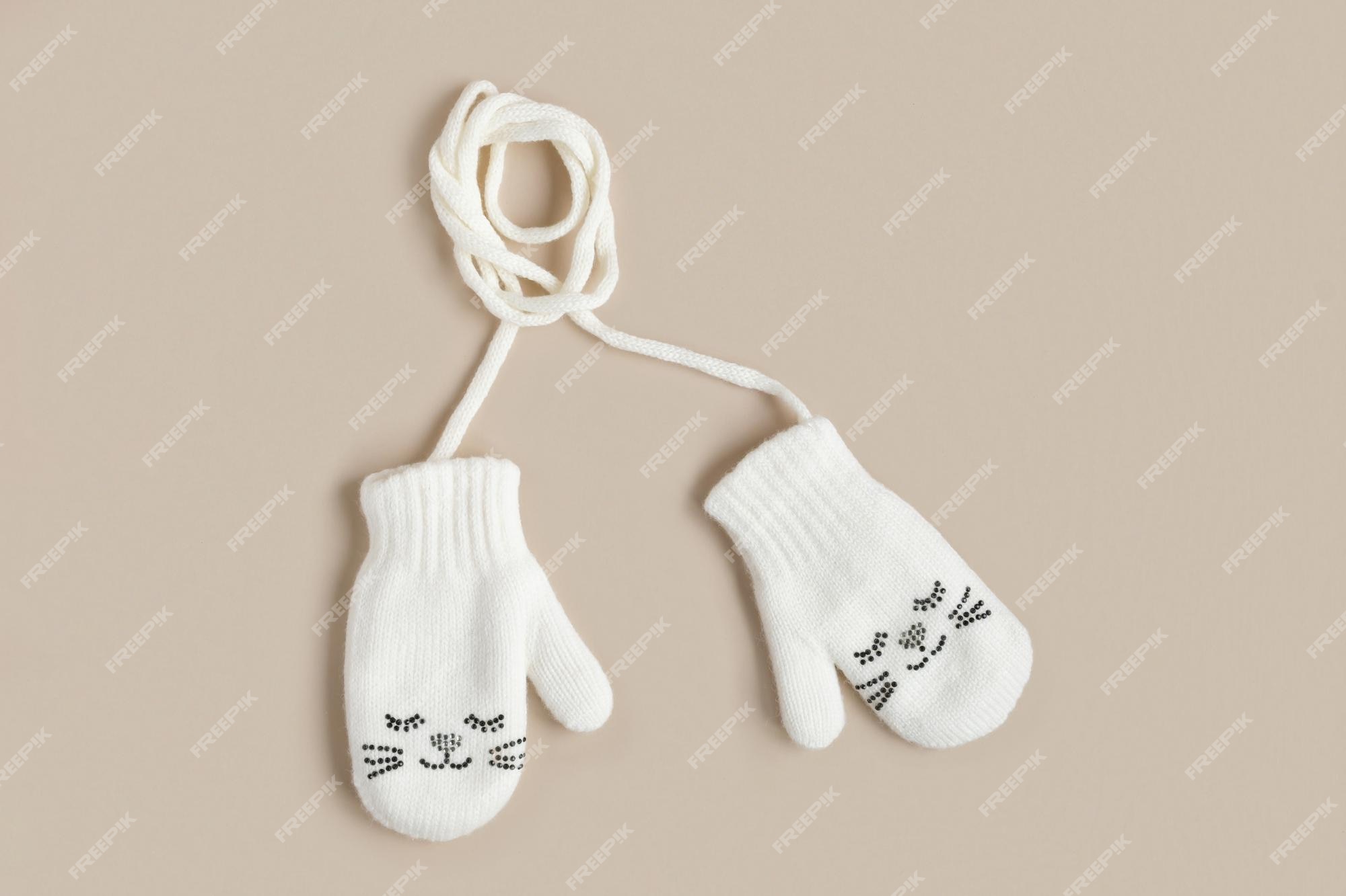 de bebé de punto blanco sobre un fondo beige natural vista superior ropa de invierno mitones sonrisa | Foto Premium