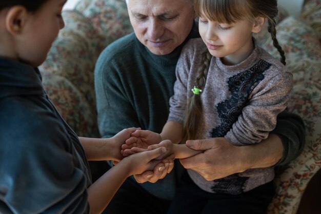 Manos de abuelo y nieta con oración.