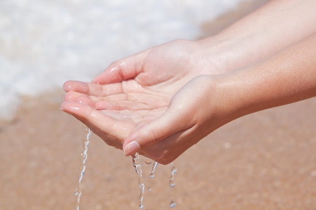 Las manos en el agua en la playa.