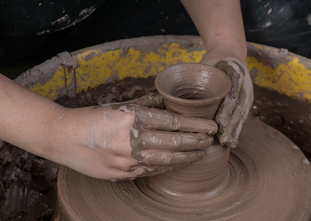 manos de un alfarero, creando un tarro de barro en el círculo