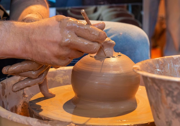 Manos de un alfarero creando una vasija de barro en el círculo