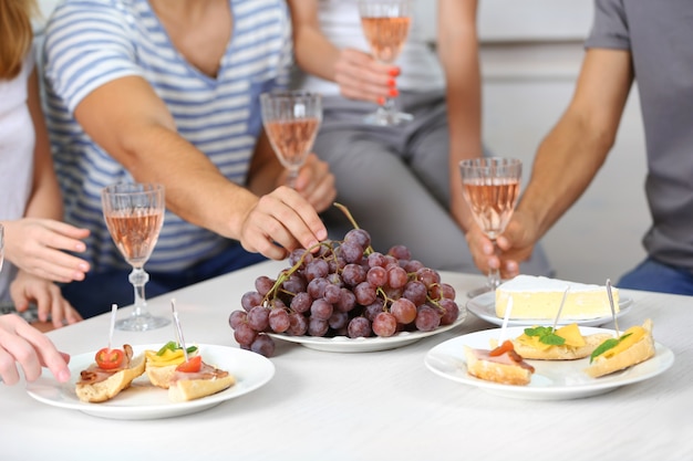 Manos de amigos con copas de vino y bocadillos, cerrar