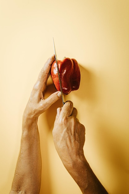 Foto manos de anciana agarrando un pimienta y un cuchillo