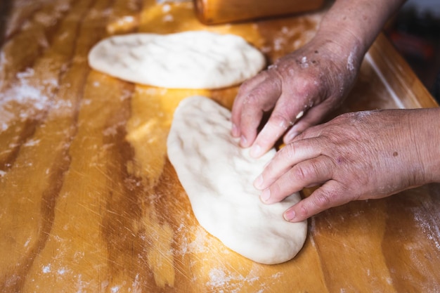 Manos de anciana amasando masa de pan Empanadas Mesa de madera