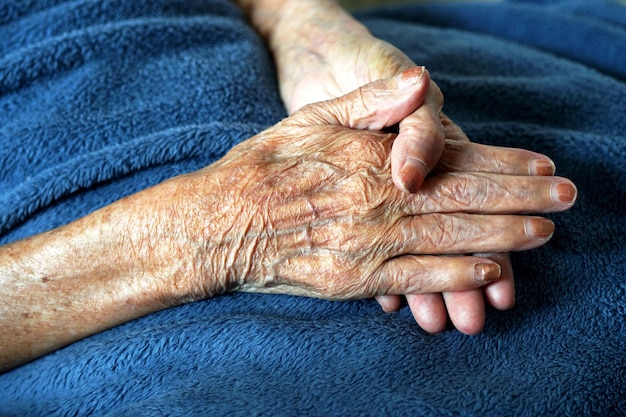 Las manos de una anciana sobre una toalla azul.