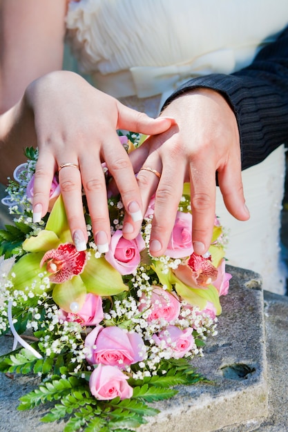 Manos y anillos en bouquet de bodas