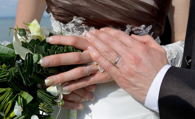 Manos y anillos en ramo de boda.