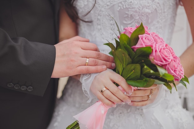 Manos y anillos en el ramo de novia.