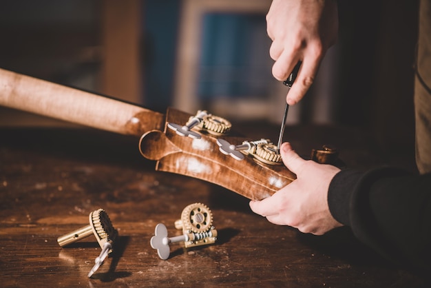 Manos de artesanos luthier atornillando, construyendo un contrabajo