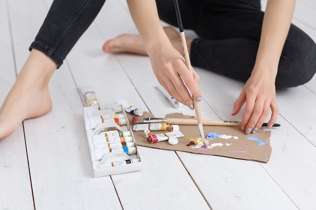 Manos del artista con pincel mezcla de colores en la paleta de cerca. Arte, creatividad, concepto de hobby, terapia antiestrés.