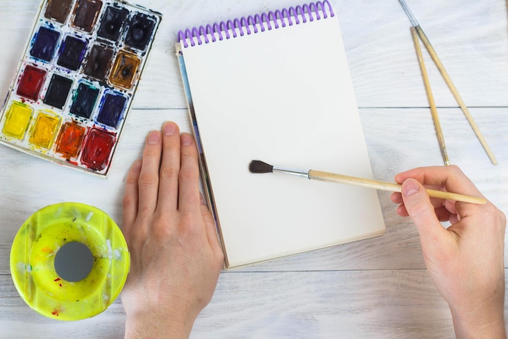 Foto las manos del artista pintan pinceles de paleta de diferentes colores la niña está dibujando las herramientas del artista para el arte real y la inspiración vista superior