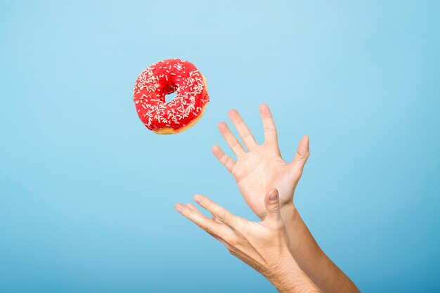 Las manos atrapan una rosquilla con glaseado. Concepto de cocción artesanal. Vista plana, vista superior