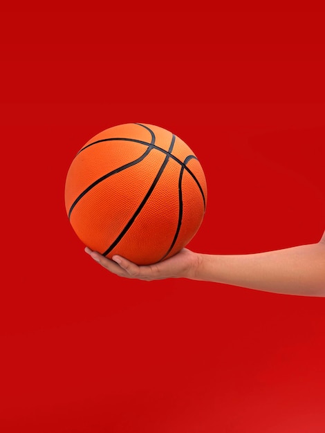 Manos y baloncesto aislado sobre fondo rojo.