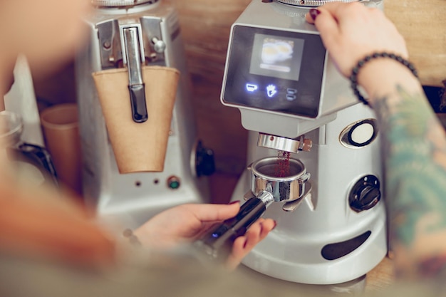 Manos de barista femenina usando una máquina de café profesional en la cafetería