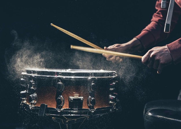 Las manos de los bateristas sostienen baquetas y tocan el tambor